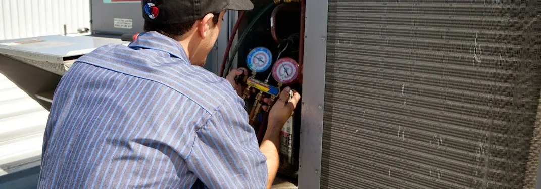 HVAC technician servicing a condenser unit in Cathedral City