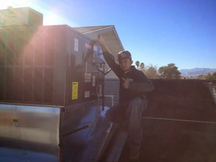 HVAC technician performing Air Duct Cleaning on a rooftop unit in Cathedral City
